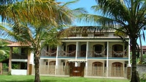A two-story colonial-style building with a balcony, surrounded by palm trees and a well-maintained lawn. - Garapuá Praia Hotel (Cairu)