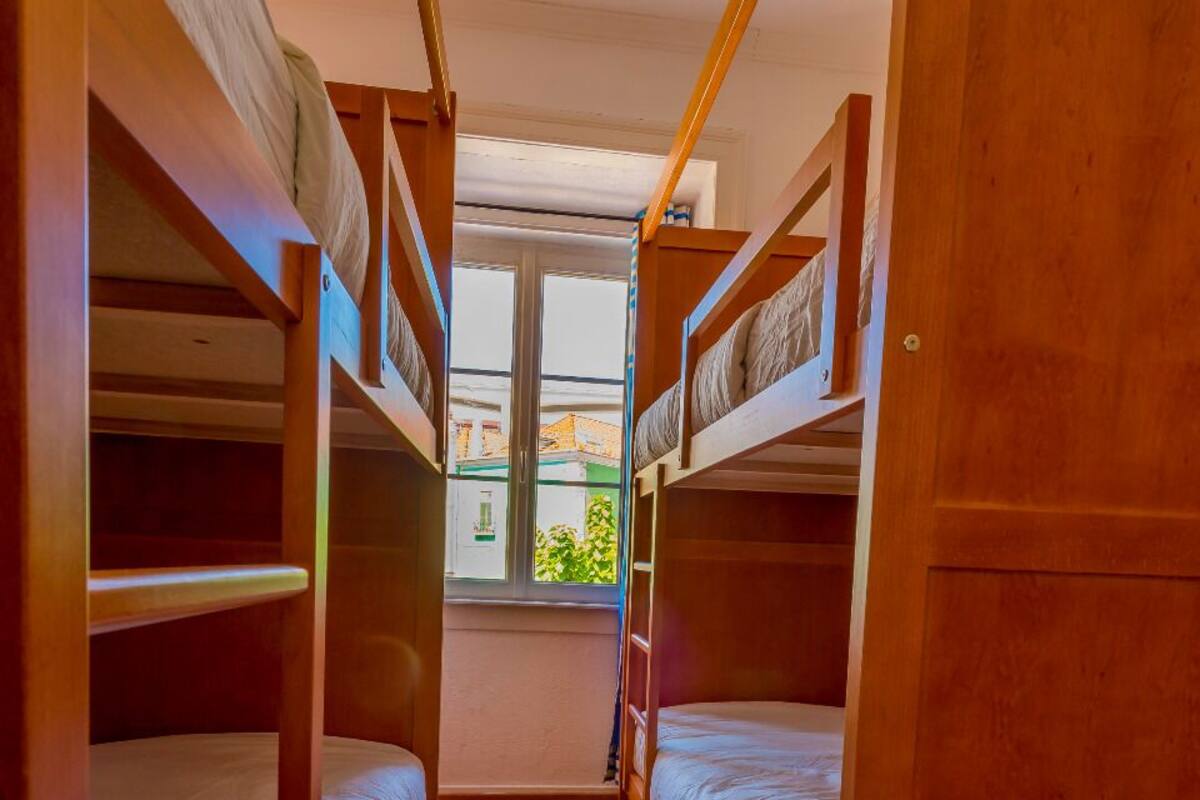 Dormitorio con literas y ventana que ofrece vistas al follaje exterior.