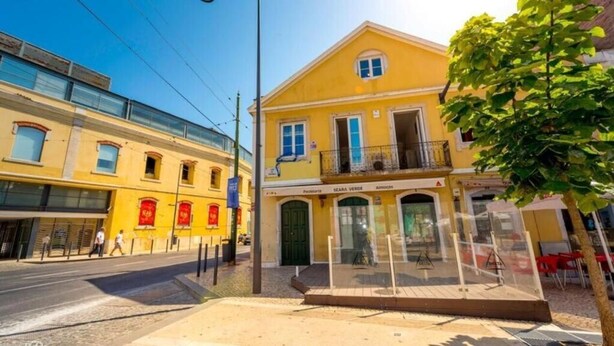 Ein gelbes Gebäude mit Balkon und Schaufenster.