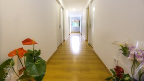 Ein Korridor mit Holzboden und weißen Wänden, der zu einem Raum mit einem Fenster führt.