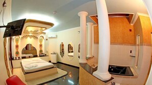 A hotel room with a bed, a red chair, a vanity with a mirror, and a bathtub. - Hotel & Motel Le Baron (Porto Ferreira)