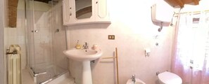 A bathroom with a glass shower enclosure, a pedestal sink, a toilet, and a cabinet above the sink. - Agriturismo Le Casette (Guardistallo)