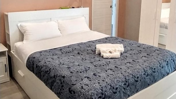 Une chambre à coucher comprenant un lit, des tables de chevet, un appareil de climatisation, une armoire et une porte.
