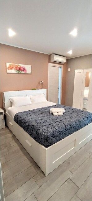 A bedroom with a bed, bedside tables, an air conditioning unit, a wardrobe, and a door. - Pretty Tiburtina Room (Rome)