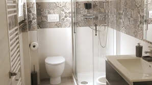 Une salle de bain moderne avec une douche à parois de verre, des toilettes et un meuble-lavabo avec un miroir.
