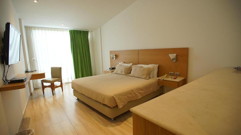 Ein Hotelzimmer mit Bett, Nachttisch, Sessel und Fernseher.