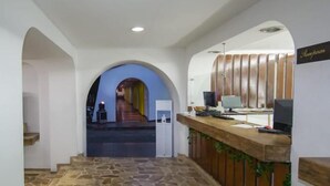 A reception area with a stone floor, a reception desk, and a staircase leading to a corridor.