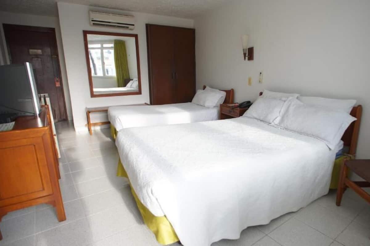 Une chambre d’hôtel avec deux lits, une télévision, une armoire et un bureau.