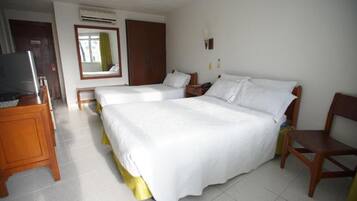 A hotel room with two beds, a TV, a wardrobe, and a desk.