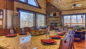 A spacious kitchen with granite countertops, wooden cabinets, and a stone fireplace.