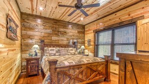 A rustic wooden bedroom with a bed, nightstands, and a ceiling fan.