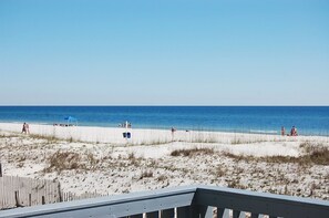 A beach with a wooden deck in the foreground. - Awbrey House (Gulf Shores)