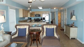 A spacious living room with a dining area, kitchen, and a hallway leading to another room. - Awbrey House (Gulf Shores)