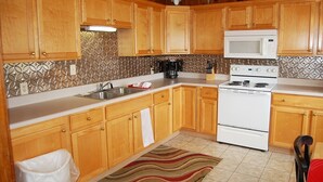 Une cuisine avec des meubles en bois, une cuisinière blanche, un four à micro-ondes et un crédence décorée.