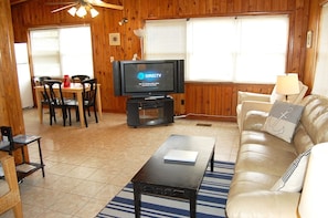 A cozy living room with a television, a sofa, a coffee table, and a dining area with chairs and a table. - Alavista Sm Pets (Gulf Shores)