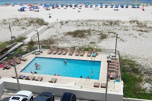 Ein Swimmingpool mit Liegestühlen und Sonnenschirmen auf einem Anwesen am Strand.