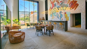 A spacious dining area with wicker furniture, large windows, and a mural on the wall. - HGTV Loft | Rooftop Pool + Gym + Views + Bar (Puerto Vallarta)
