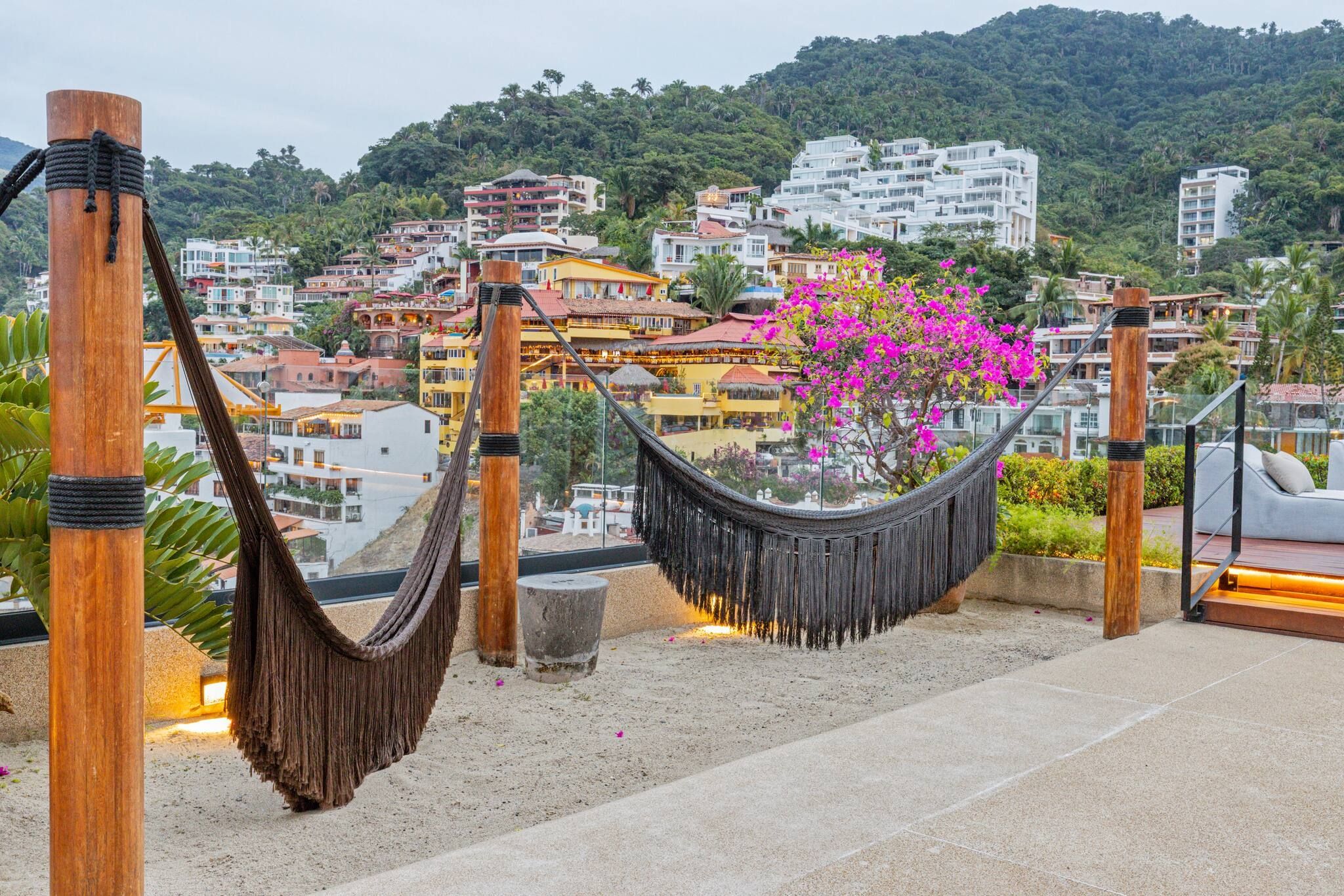 Un hamac sur un toit-terrasse, avec vue sur une ville perchée sur une colline.