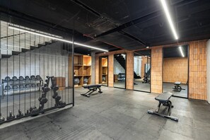 A gym with exercise equipment, wooden walls, and a mirrored wall. - HGTV Loft | Rooftop Pool + Gym + Views + Bar (Puerto Vallarta)