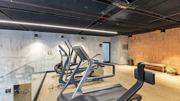 Ein Fitnessraum mit Trainingsgeräten, Holzboden und Backsteinwand.