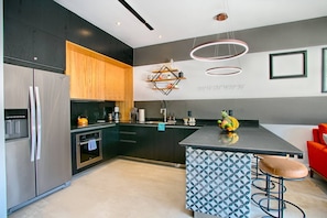 A modern kitchen with a central island, stainless steel appliances, and a unique geometric backsplash.