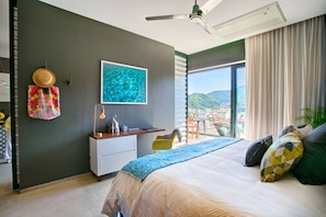 A modern bedroom with a large bed, a desk, and a view of a cityscape. - HGTV Loft | Rooftop Pool + Gym + Views + Bar (Puerto Vallarta)