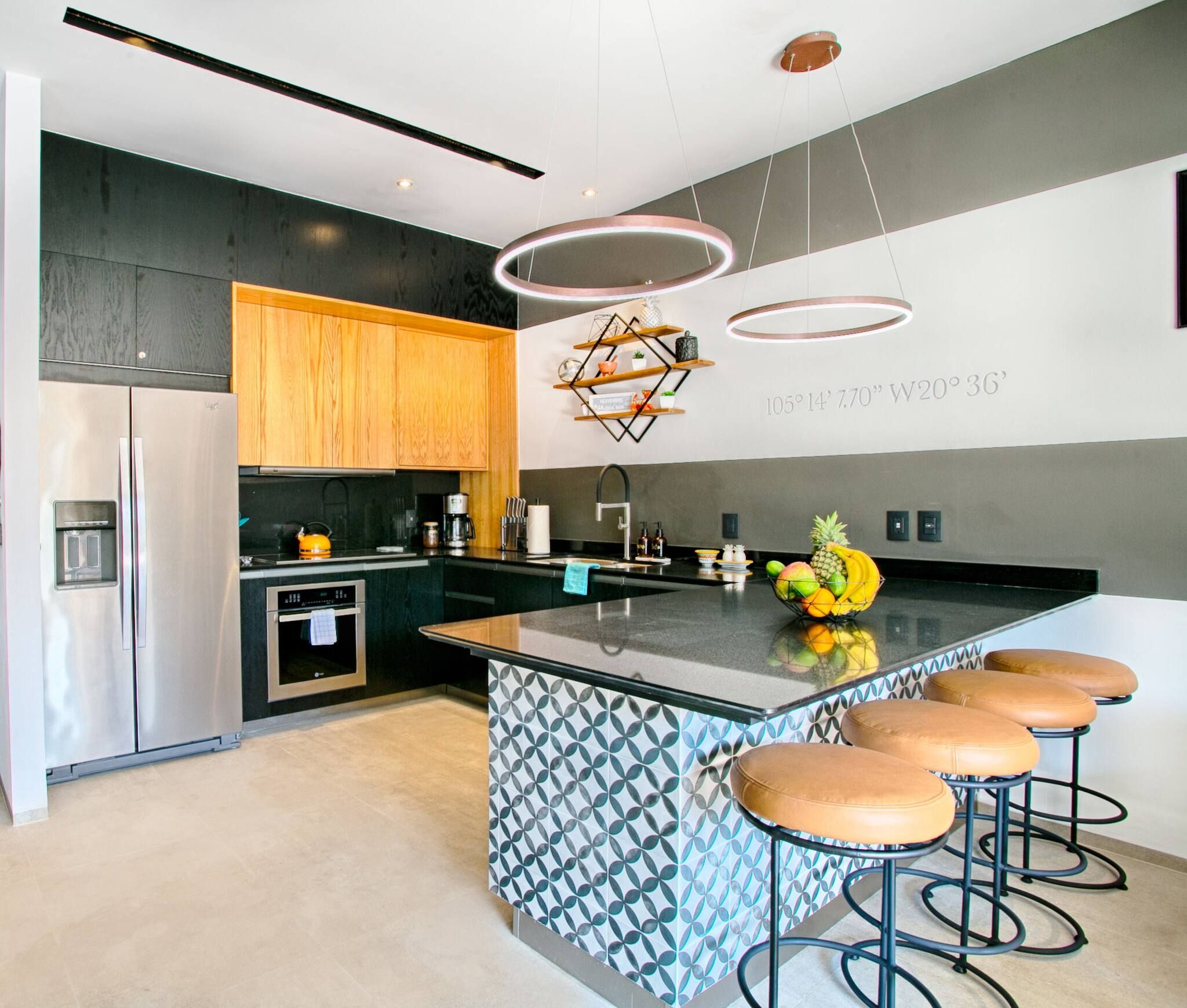 A modern kitchen with a central island, bar stools, and a geometric patterned backsplash.