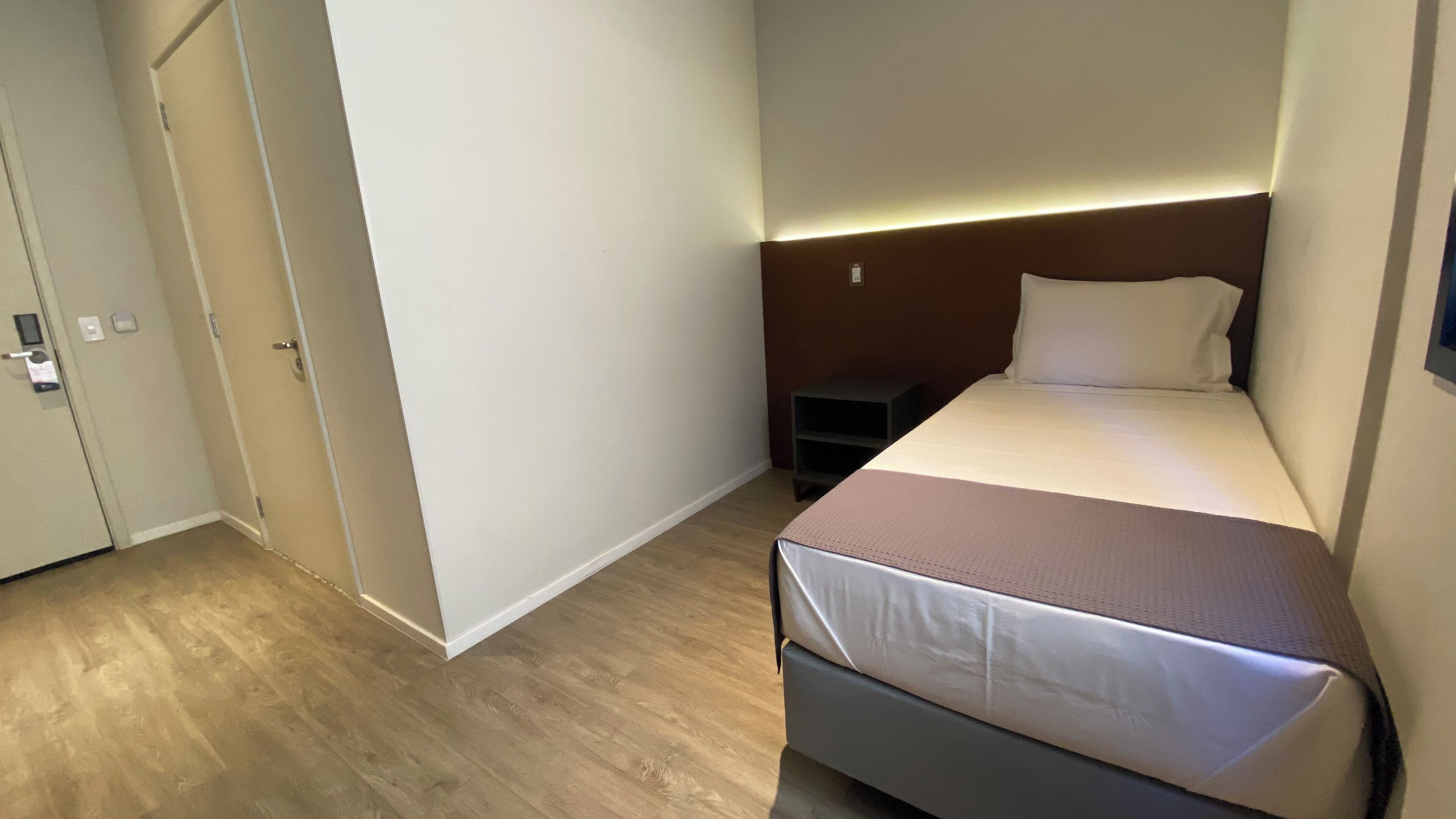 A small, neatly arranged bedroom with a bed, bedside table, and a nightstand.