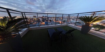 Een terras op het dak met uitzicht op een stadsgezicht in de schemering.