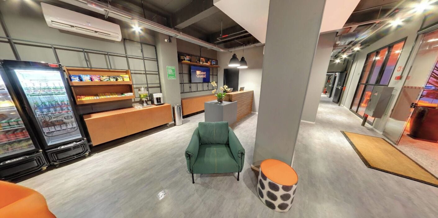 A modern hotel lobby with a reception desk, seating area, and vending machines.