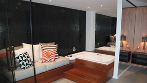 Un baño moderno con tocador de madera, una bañera grande y zona de ducha con mampara de vidrio.