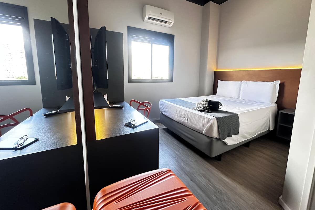 Habitación de hotel con cama, escritorio, silla y televisor.