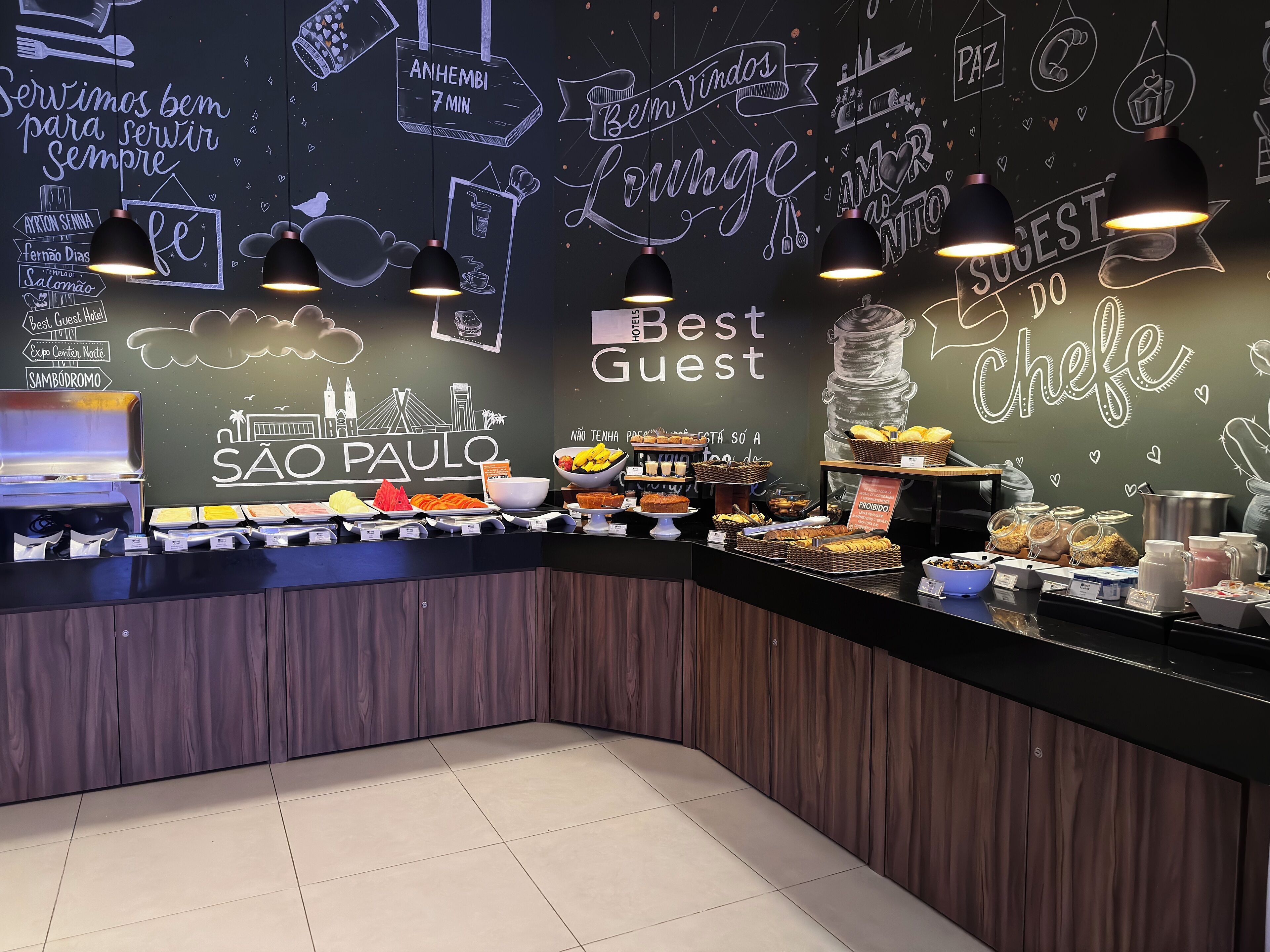 A buffet counter with various food items and a chalkboard wall with text and drawings.