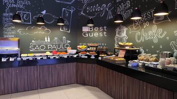 A buffet counter with various food items and a chalkboard wall with text and drawings.