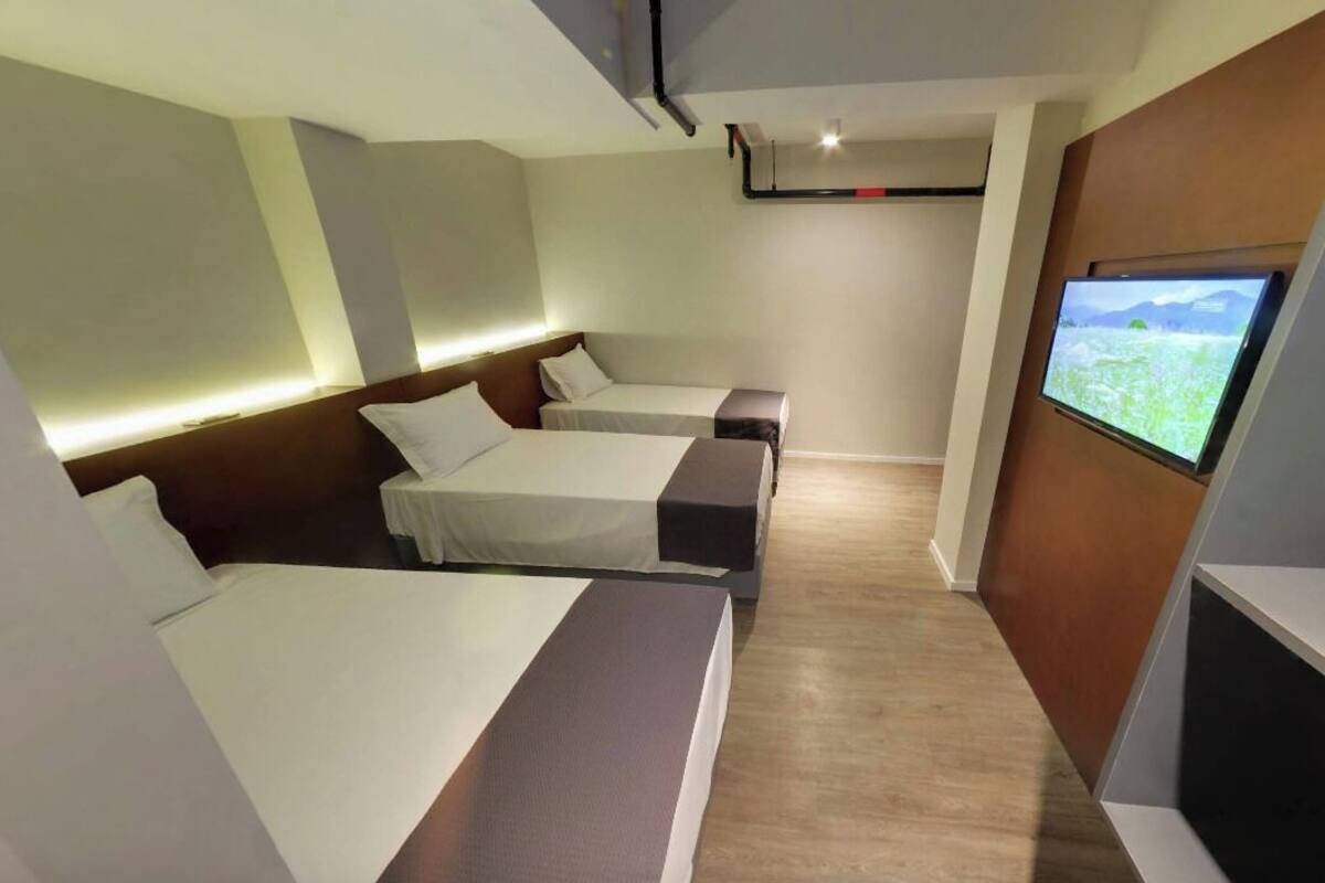 Habitación de hotel moderna con dos camas, un televisor de pantalla plana y una pared de acento de madera.