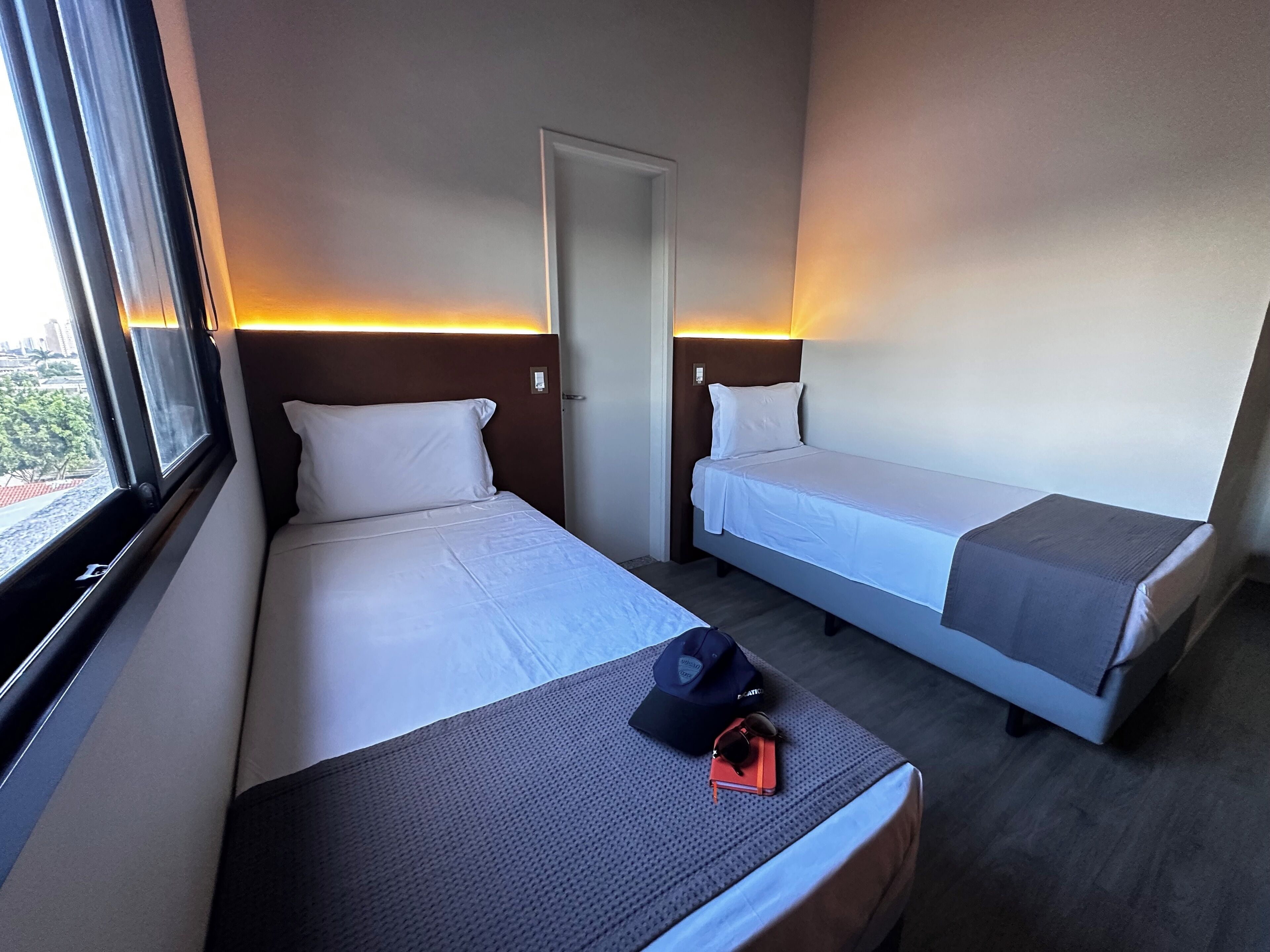 Una habitación de hotel con dos camas individuales, una ventana y una puerta.