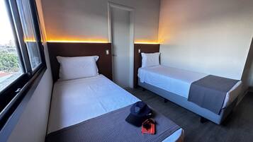 Una habitación de hotel con dos camas individuales, una ventana y una puerta.