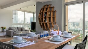 A dining area with a wooden table set for four, a grey sofa, and a city view through large windows. - New Modern Ocean View (Panama City)