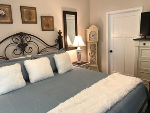 Cozy retreat with a large bed, nightstand, and TV, surrounded by artwork.