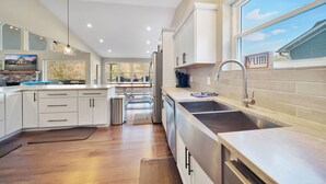 Una cocina moderna con gabinetes blancos, electrodomésticos de acero inoxidable y un amplio ventanal.