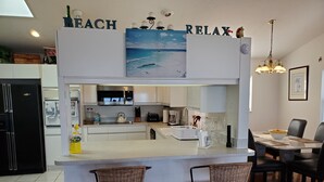 Una cucina moderna con un'isola centrale, sgabelli da bar e un'area pranzo con tavolo e sedie.