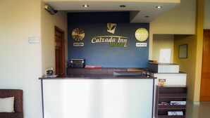 A reception desk with a clock, a sign for New York and Mexico, and a Calzada Inn Hotel sign.