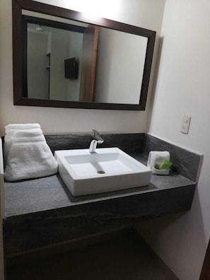 A bathroom with a white sink, a mirror above it, and a towel on the counter.