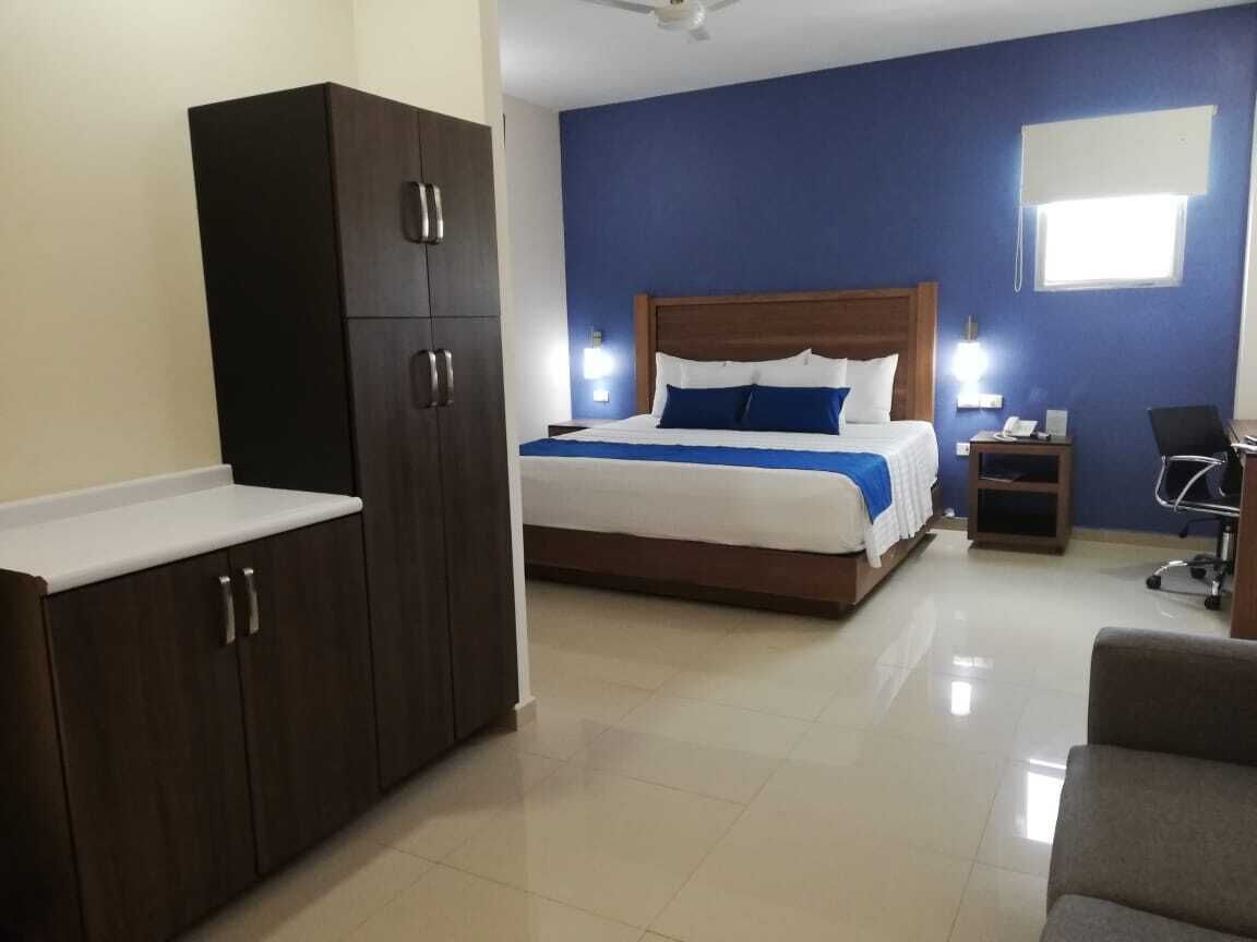 A hotel room with a bed, a wardrobe, a desk, and a chair.