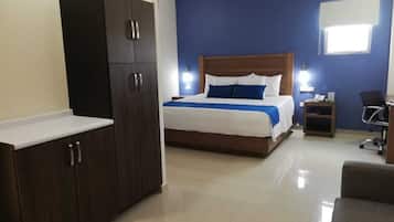 Una habitación de hotel con cama, armario, escritorio y silla.