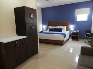 A hotel room with a bed, a wardrobe, a desk, and a chair.
