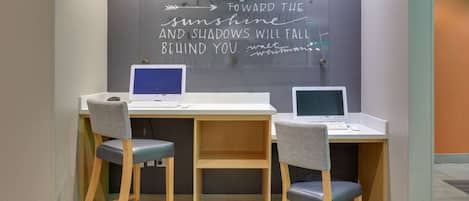 Een werkruimte met twee bureaus, elk met een laptop en een stoel. Een inspirerende quote staat op de muur.
