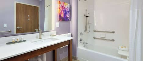 A bathroom with a wooden vanity, a large mirror, a shower with a glass door, and a white bathtub.