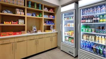 Zona de venta automática con varios estantes llenos de aperitivos y bebidas.