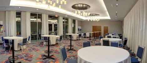A conference room with round tables, chairs, and a patterned carpet.